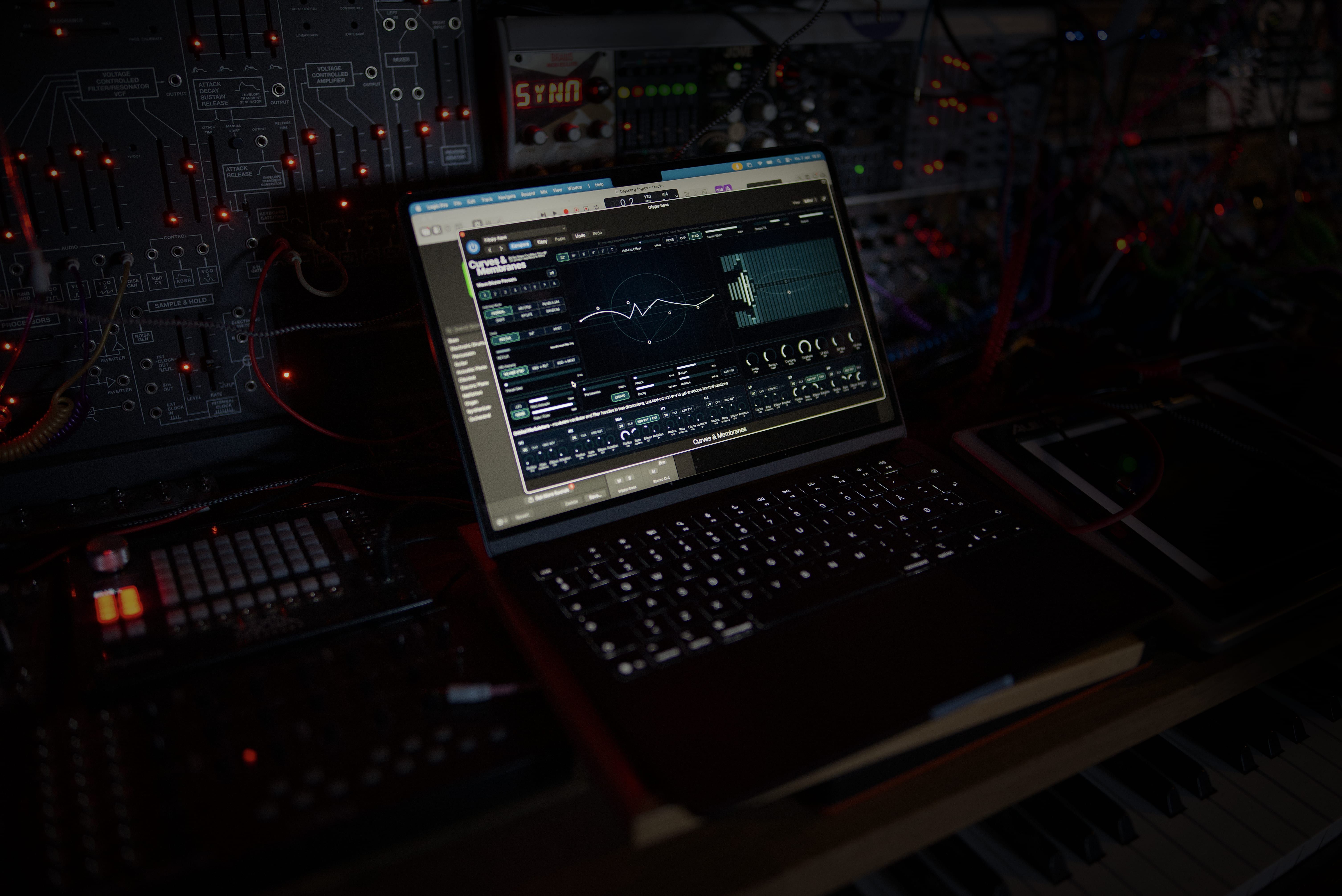 A macbook air in front of some modular synthesizers